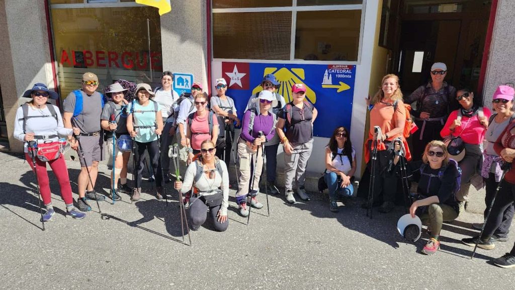Grupo de peregrinos listos para iniciar el Camino de Santiago organizado frente a un albergue.